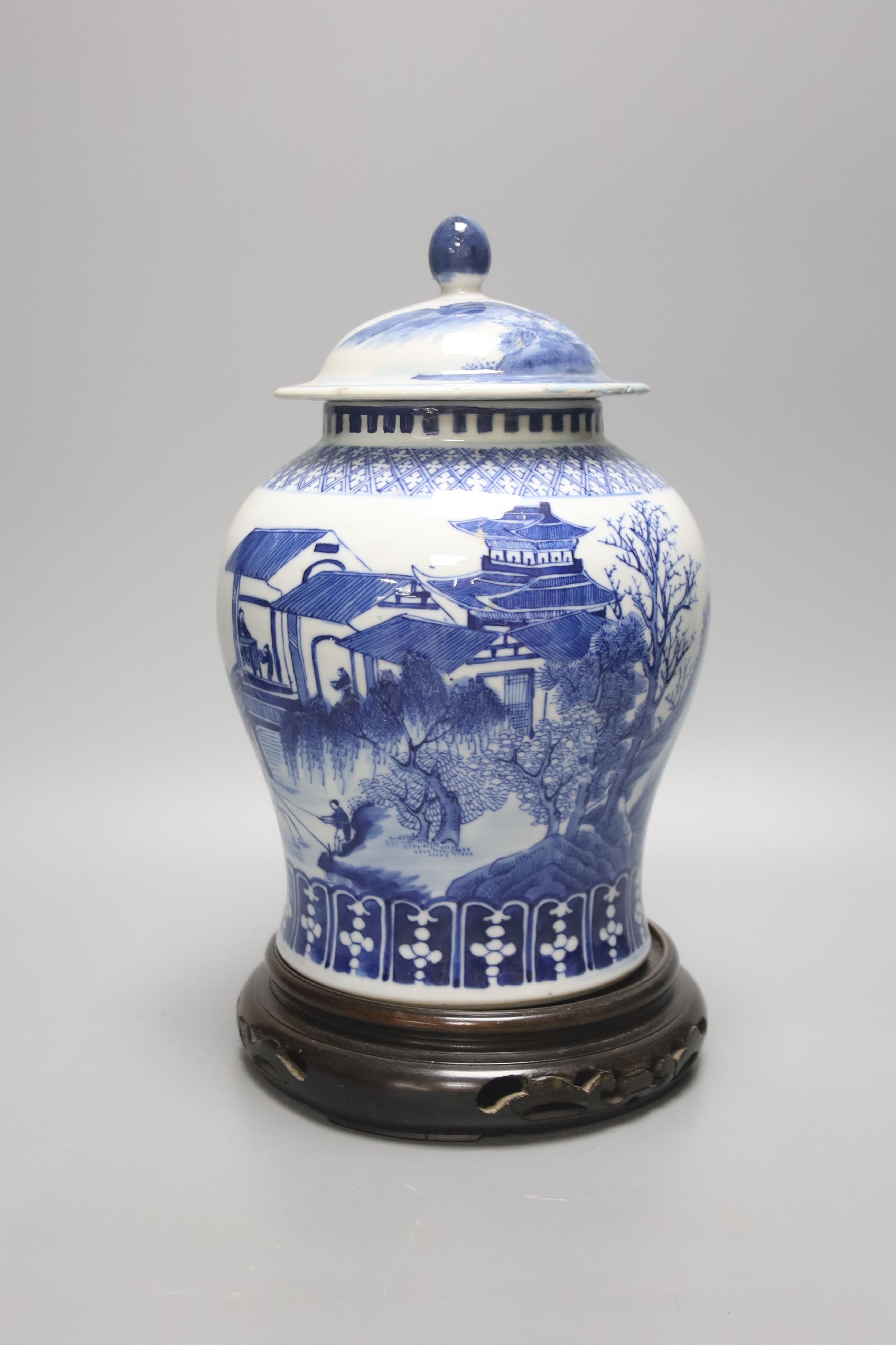 A late 19th / early 20th century Chinese blue and white landscape jar and cover, wood stand 30cm total height